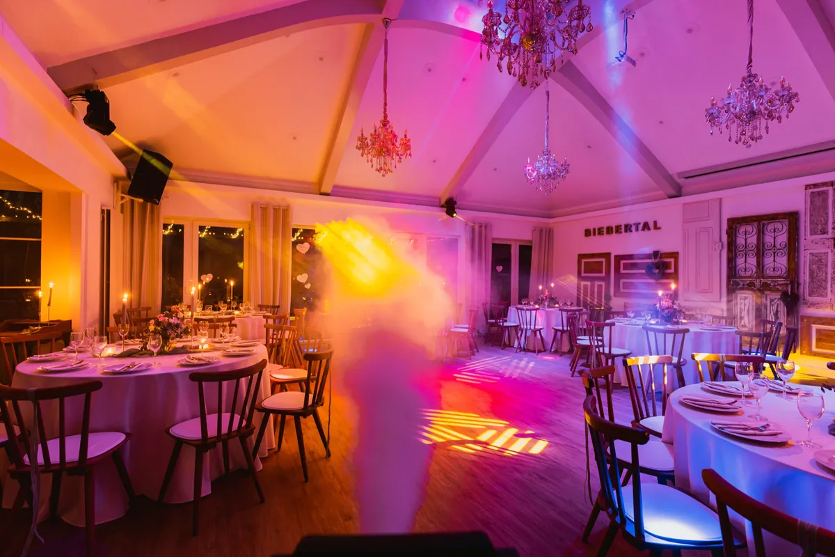 Festlich gedeckter Festsaal im Hotel Biebertal mit Kronleuchtern, Kerzen und warmer rosa-goldener Lichtstimmung