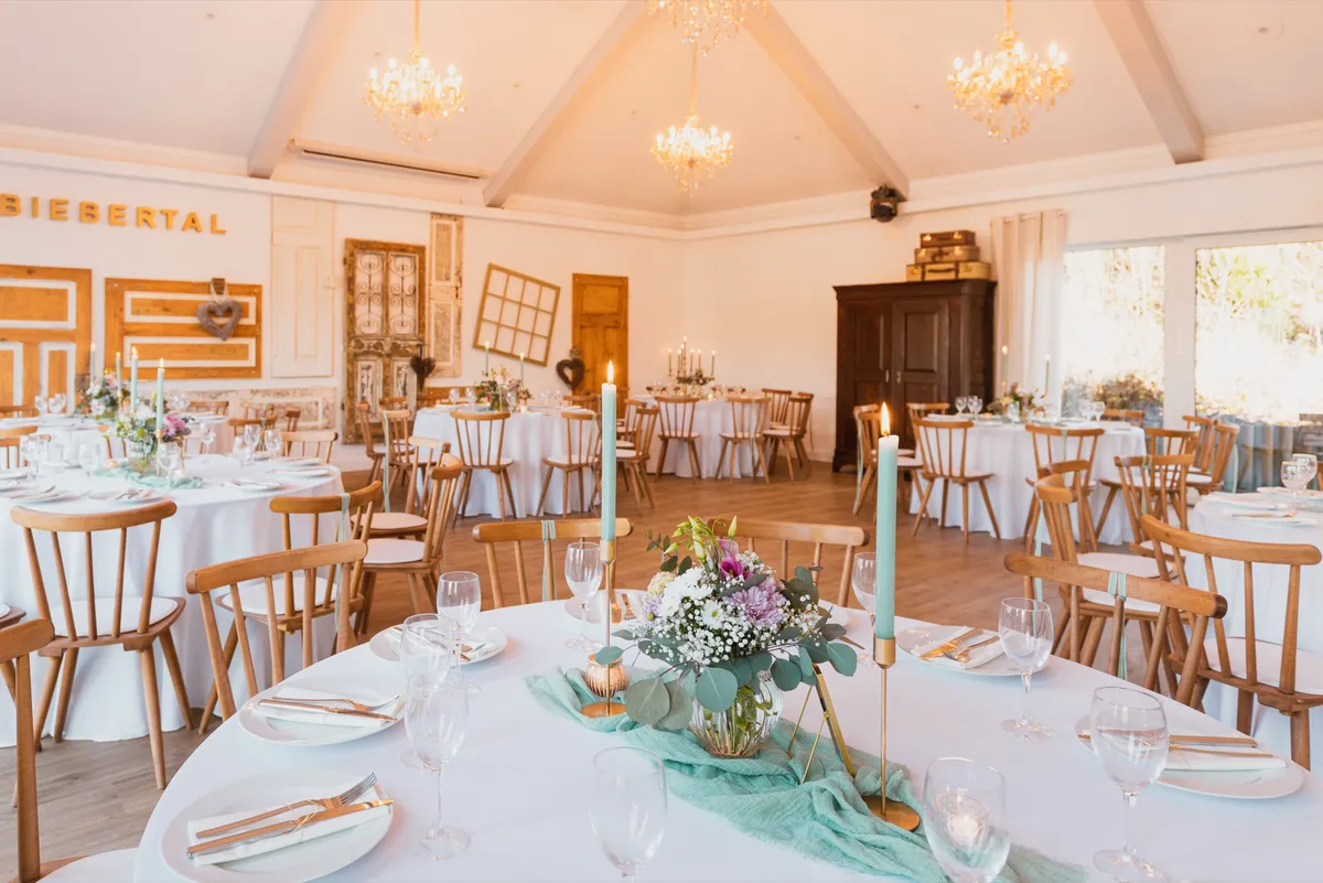 Festsaal mit antiker Türenwand, Kronleuchtern und Tafel mit mintgrüner Kerzendeko