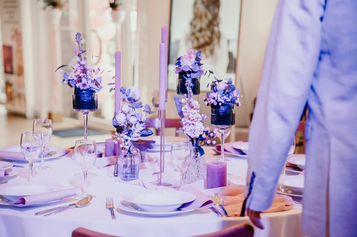Gedeckter Hochzeitstisch in Flieder und Rosé mit Kerzen, Trockenblumen und Weingläsern