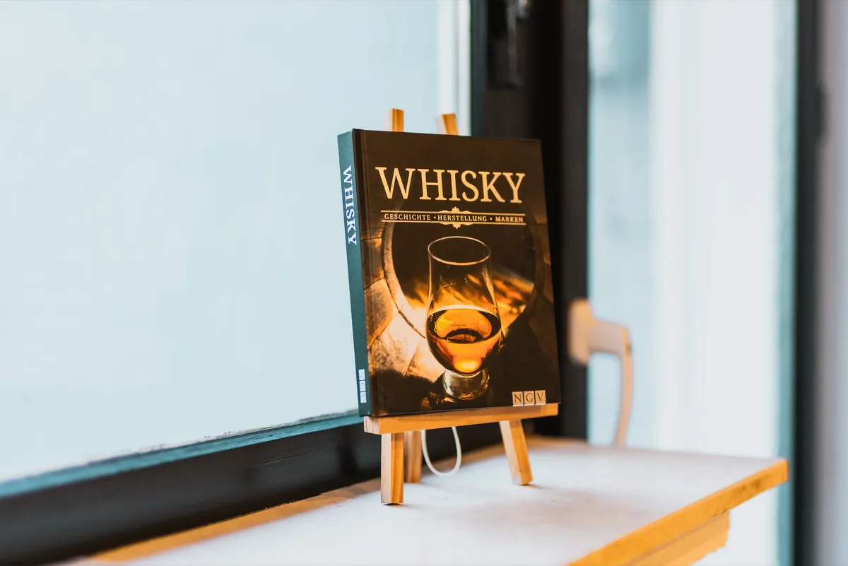 Whisky-Buch auf kleiner Staffelei an der Fensterbank der Bar